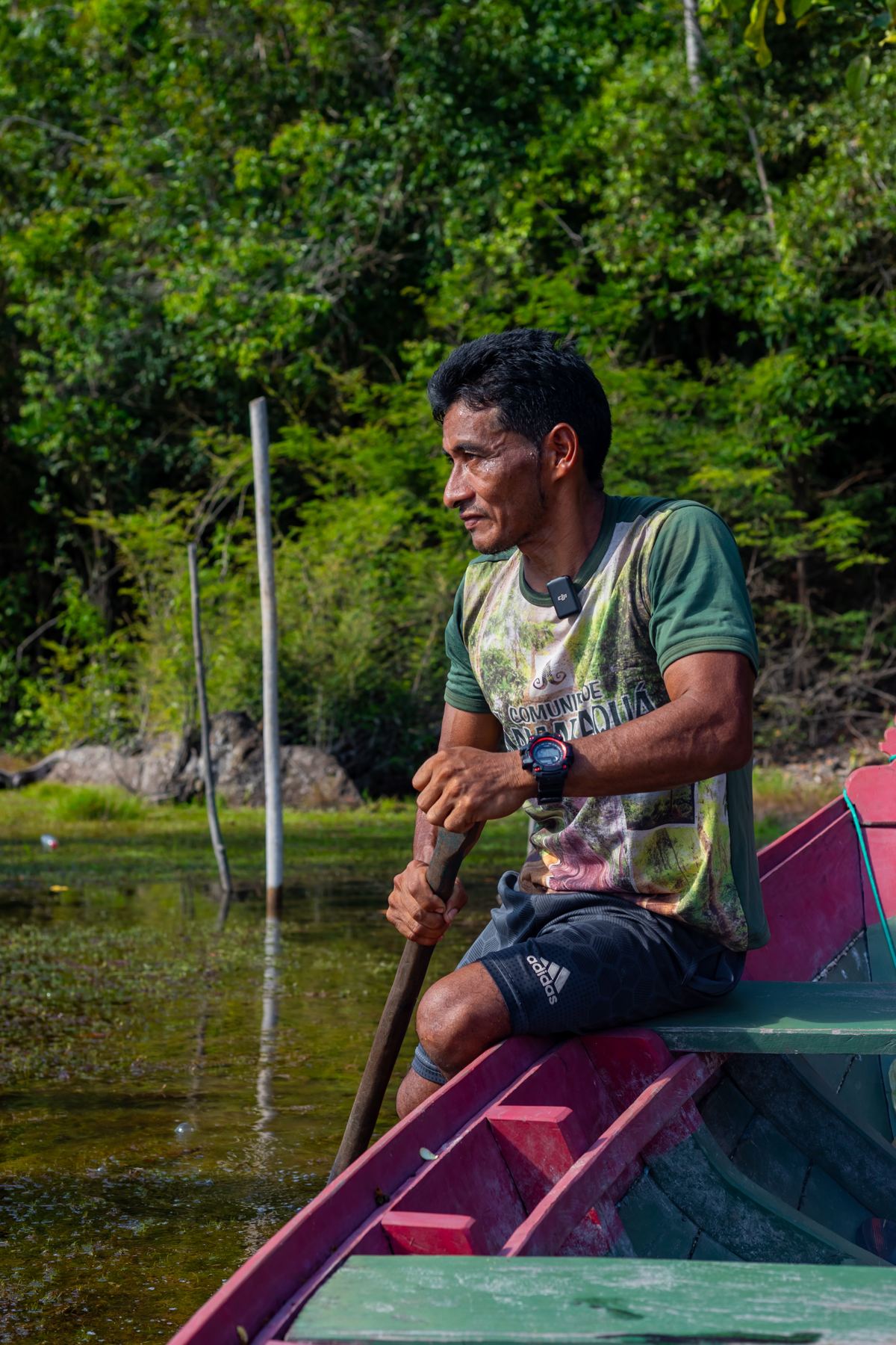 Homem remando uma canoa num rio cercado de vegetação