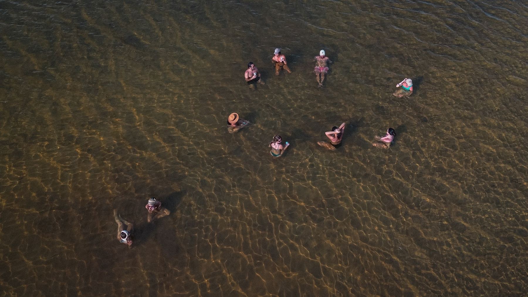 Grupo de pessoas em círculo dentro do rio, visto do alto